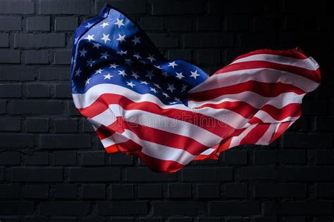 Dynamic Waving United States Flag In Front Of Black Brick Wall