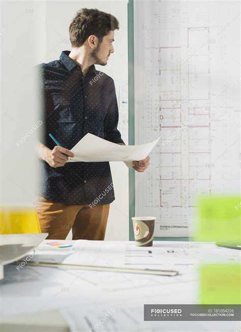 Young Architect In Office Looking At Construction Plan — Documents