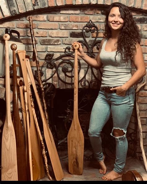 A Woman Standing In Front Of A Brick Fireplace Holding Two Paddles And Posing For The Camera