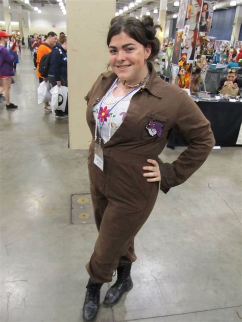 A Woman In A Brown Suit And Black Boots Posing For The Camera With Her