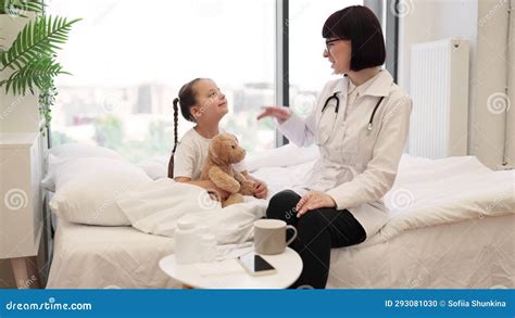 Pediatrician And Girl Giving High Five To Each Other On Bed Stock