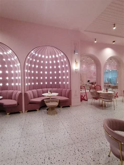 The Interior Of A Restaurant With Pink Walls And Round Tables Chairs