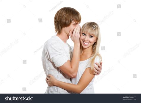 Young Happy Couple Love Smiling Man Telling A Secret To A Girl She Is Looking At Camera