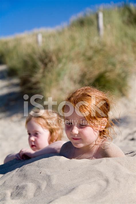 Children Buried In The Sand At Beach Stock Photos