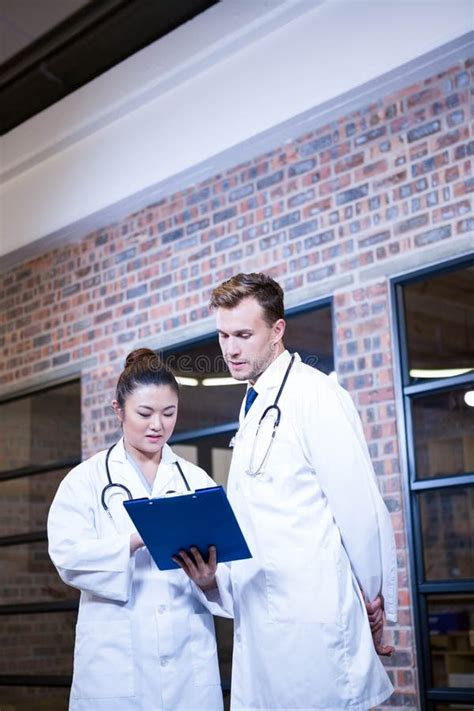 Two Doctors Looking At Clipboard And Discussing Near Library Stock