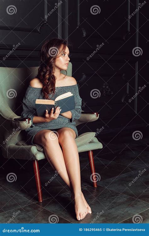 Beautiful Woman Sitting In A Chair And Reading A Book Stock Image