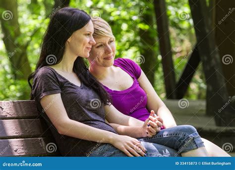 Girlfriends Sitting On Park Bench Holding Hands Horizontal Stock Image