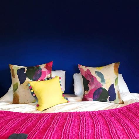 A Bed With Colorful Pillows And Blankets On It In A Room That Has Blue