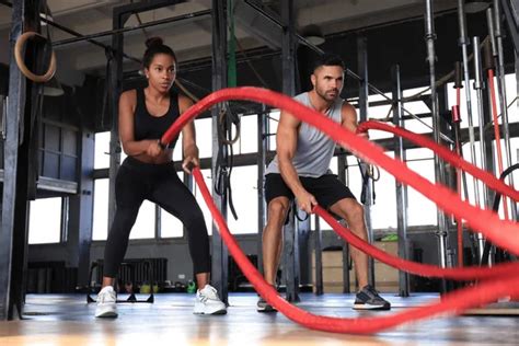 Athletic Young Couple With Battle Rope Doing Exercise In Functional