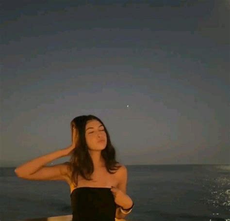 A Woman Standing On Top Of A Boat In The Ocean Under A Moon Filled Sky