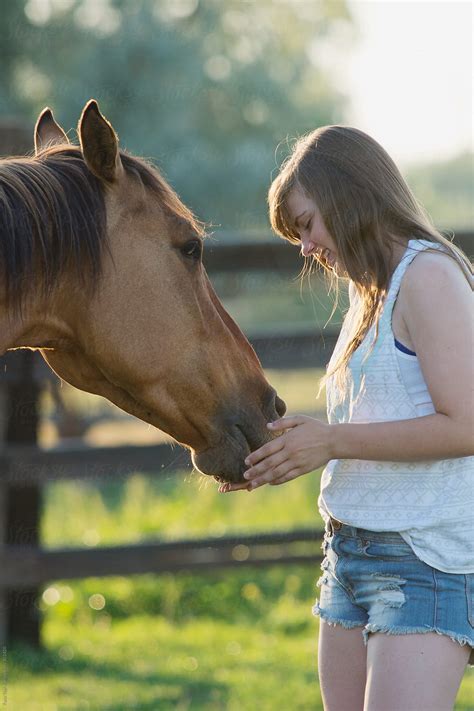 Teen Girl Pets The Muzzle Of Her Horse Del Colaborador De Stocksy