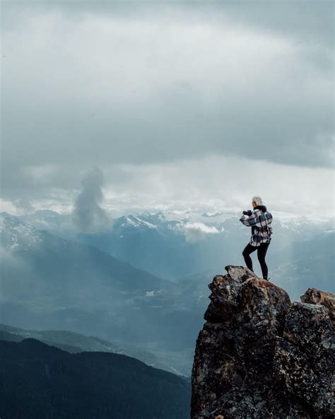 Person Standing On Top Of Rock Mountain During Daytime