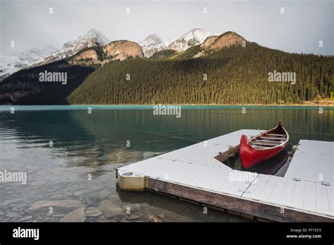 Red Canoe And Dock In Lake Louise With Snow Covered Mountains Banff