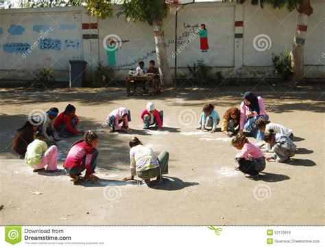 Female Teacher In Head Scarf At School Collecting The Girls In Circle