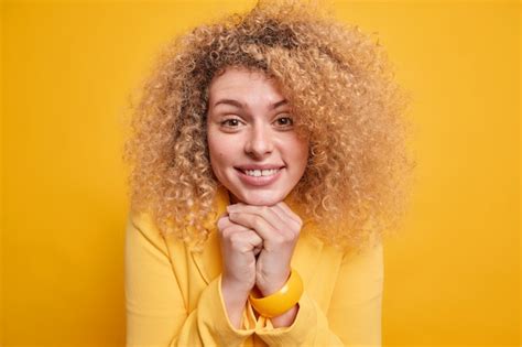 Free Photo Headshot Of Lovely Curly Haired Woman Keeps Hands Under