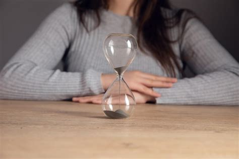 Premium Photo Woman Sitting In Front Of An Hourglass