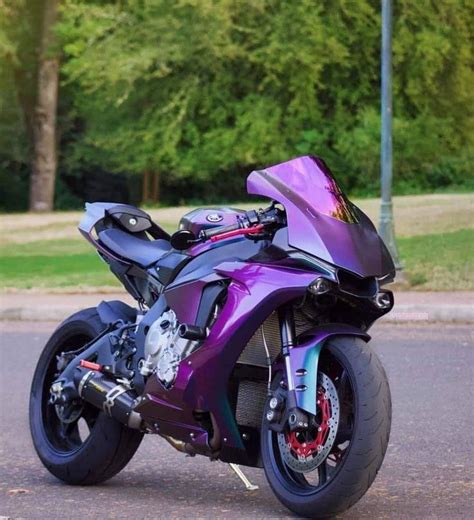A Purple Motorcycle Is Parked On The Side Of The Road In Front Of Some