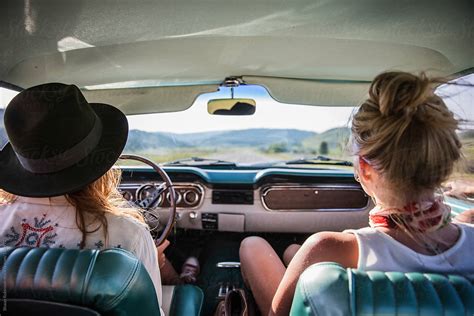 Two Women Driving In A Vintage Car Looking Out At The Open Road By