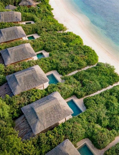 An Aerial View Of Some Huts On The Beach With Water And Trees In The