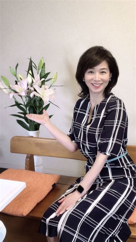 A Woman Sitting On A Bench Holding A Vase With Flowers In It And Smiling At The Camera