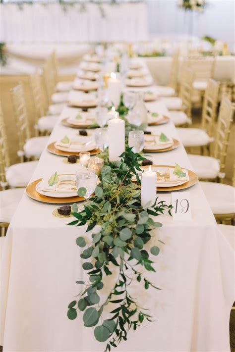 Eucalyptus Table Runner With Gold Chargers And White Pillar Candles Kate Beck Gold Wedding