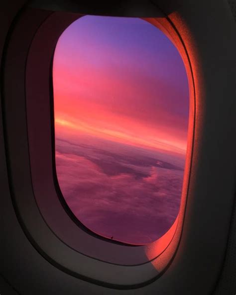 an airplane window with the view of clouds and sky at sunset or dawn from inside