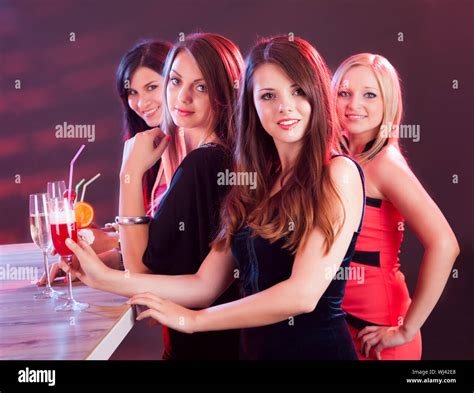 Four Beautiful Fashionable Women On A Night Out Standing At A Bar