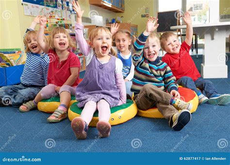 Group Of Pre School Children Answering Question In Classroom Stock