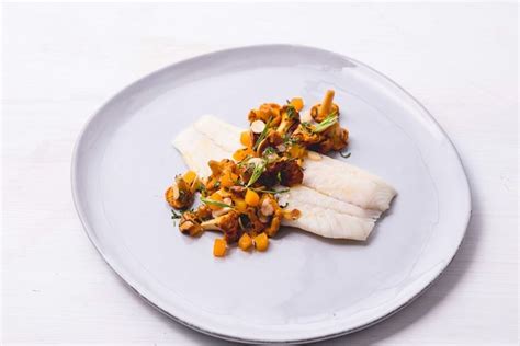 A White Plate Topped With Fish And Vegetables