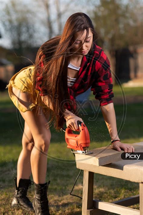 Image Of A Dark Haired Woman Smiles Cutting A Wooden Board With An