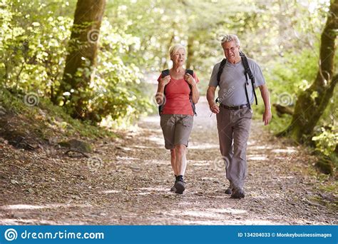 senior couple hiking along woodland path in lake district uk together stock image image of