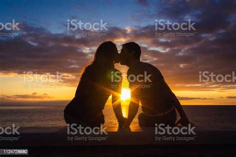 Man And Woman Sitting By The Sea Kissing At Sunset At Meloneras Beach