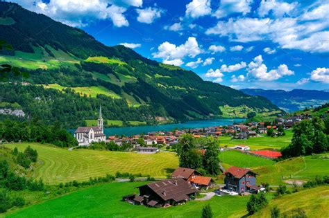 An Aerial View Of A Small Village In The Mountains With Green Grass And