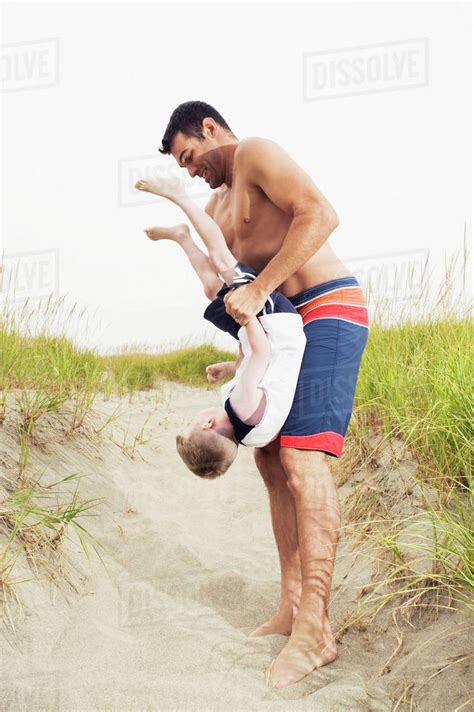 Father Holding Son Upside Down On Beach Stock Photo Dissolve