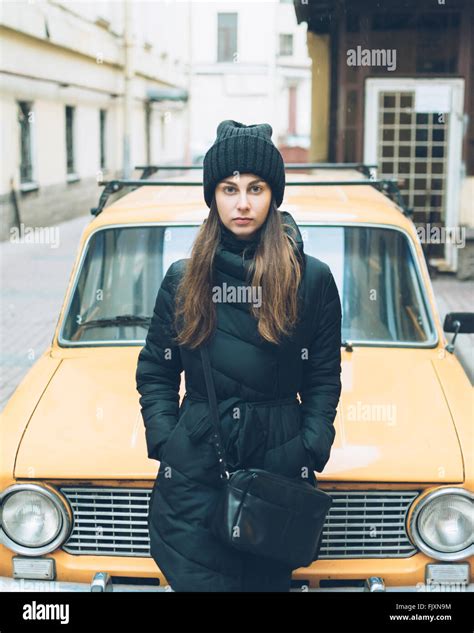 Portrait Of Beautiful Young Woman Leaning On Car Parked At Street Stock