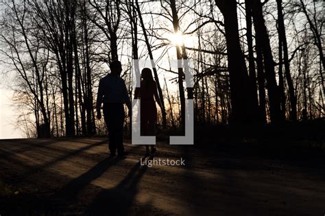 A Couple Walking Holding Hands Down A Dirt Road — Photo — Lightstock