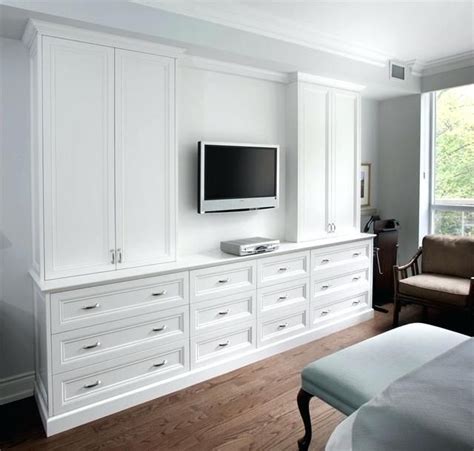 A Bedroom With White Furniture And A Flat Screen Tv Mounted On The Side