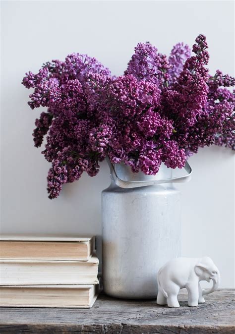 An Elephant Figurine Sitting Next To A Vase Filled With Purple Flowers