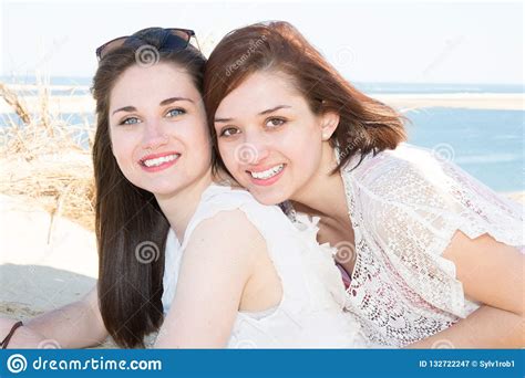 Lesbian Couple Standing At The Beach In Love Looking Into Camera Stock