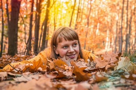 Attractive Woman Is Lying Over Autumn Leaves In Park Stock Image