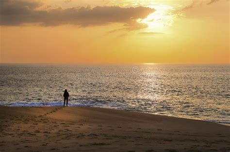 Woman Stands On The Ocean And Looks At The Sunset Stock Photo Image