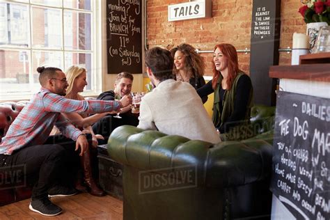 Group Of Friends Enjoying Drink In Bar Sitting On Sofa Stock Photo Dissolve