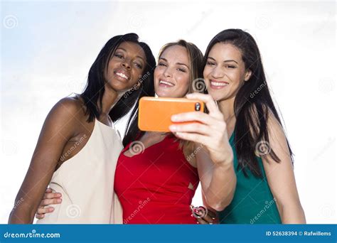 Portrait Of Three Women Taking Selfies With A Smartphone Stock Photo