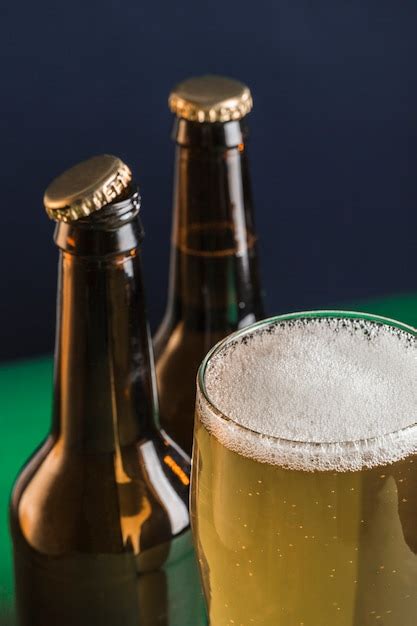 Premium Photo Two Dark Beer Bottles A Glass Of Beer And Foam On A