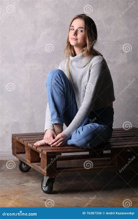 Teen With Bended Knee Sitting On A Deck Gray Background Royalty Free Stock Photography