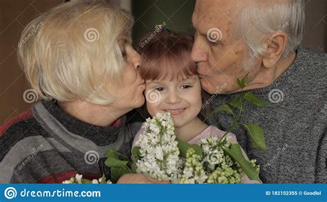 Abuelo Y Abuela Besando En La Cabeza A Su Nieta En Casa Imagen De