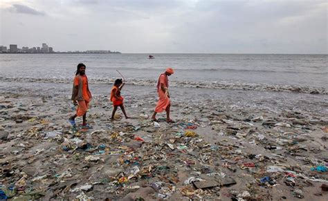 Three People Are Walking On The Beach Covered In Trash
