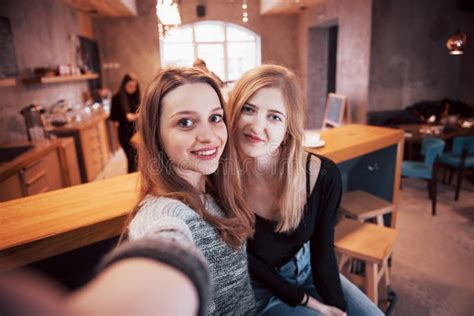 Two Friends Drinking Coffee In A Cafe Taking Selfies With A Smart Phone And Having Fun Making