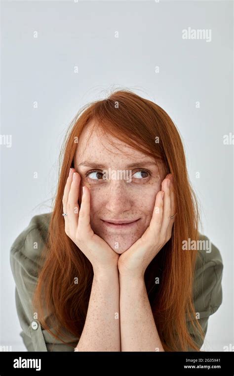 Positive Female With Ginger Hair Keeping Hands On Cheeks And Looking