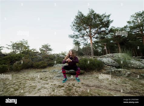 Mid Adult Woman Doing Squatting Exercise In Forest Stock Photo Alamy